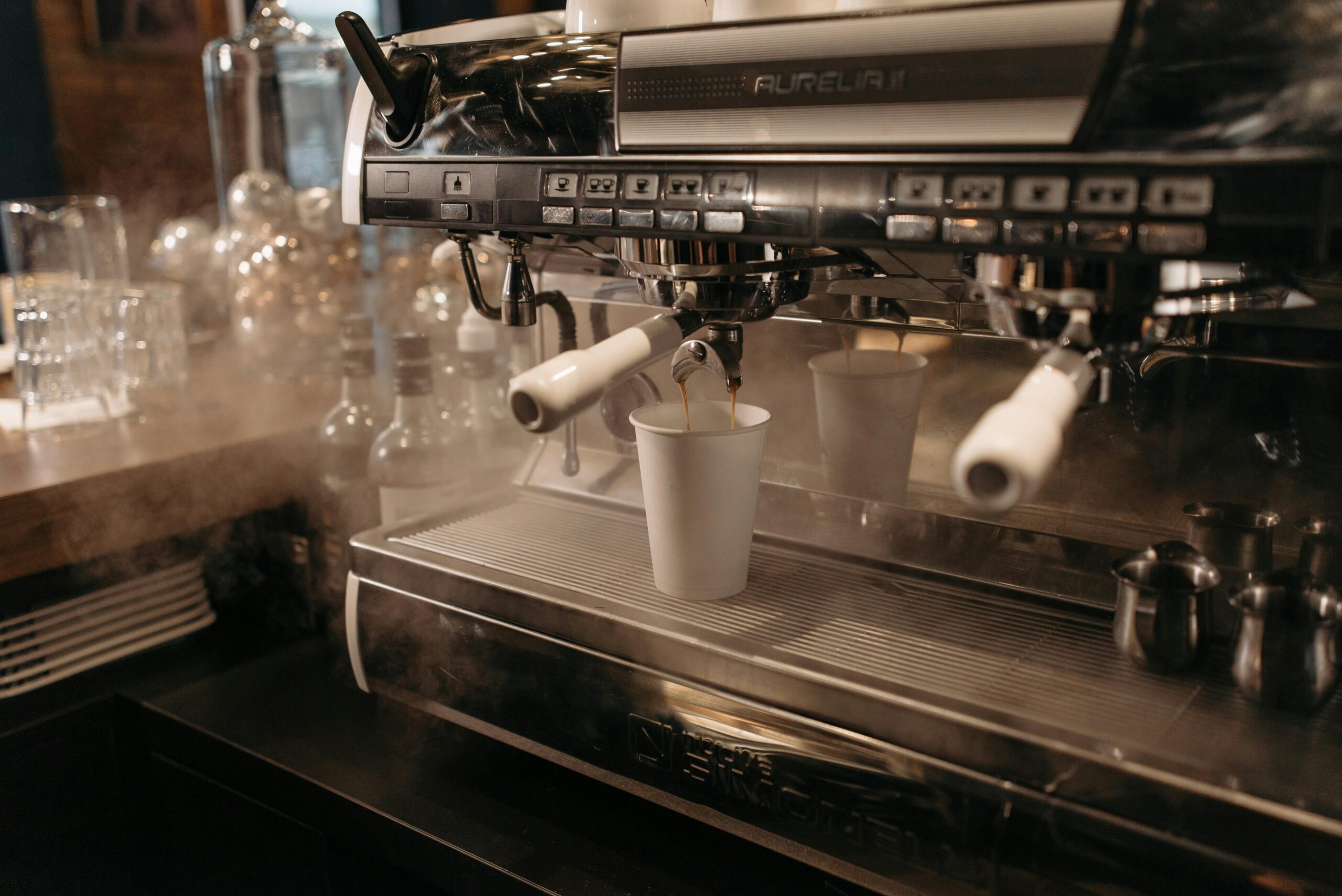 A Steaming Hot Coffee Pouring Out from a Coffee Machine to a Cup